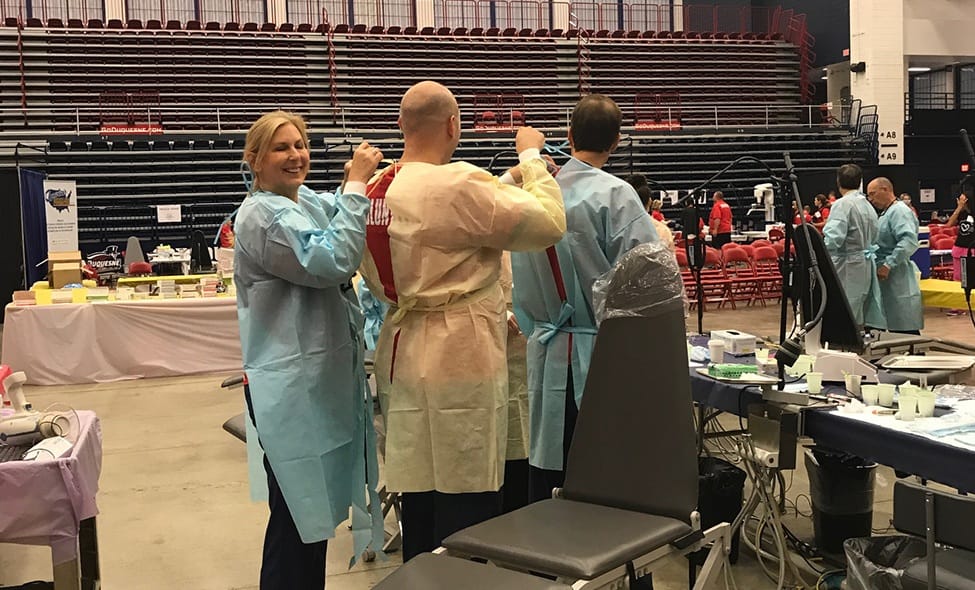 Dentists and team members putting on protective equipment at community event