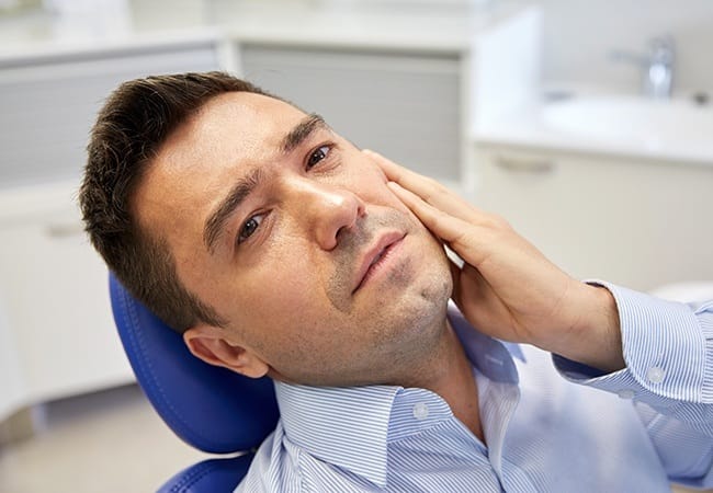 Man with a toothache holding his cheek at the dentist's office