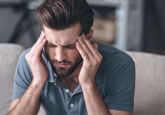 Man in need of T M J therapy holding head in pain