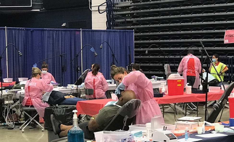 Large group of people performing oral hygiene and dental services at community event