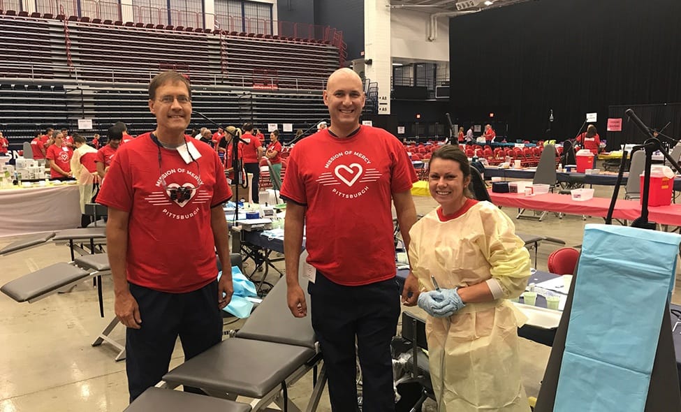 Dentists and patient smiling together at community event