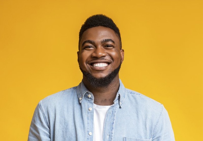 man smiling against a yellow background 