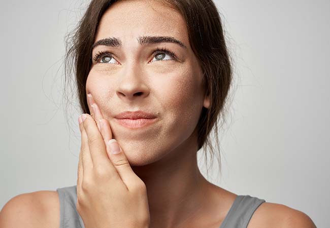 Woman with a toothache in Pittsburgh holding her cheek