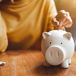 Person placing coin into a piggy bank