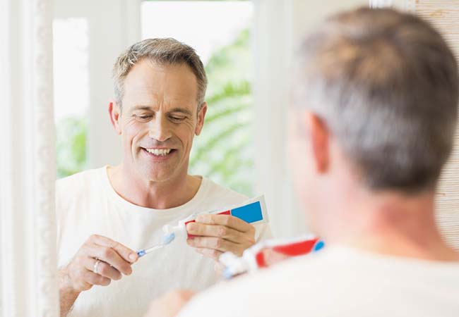 Man preventing dental emergencies in Pittsburgh by brushing his teeth