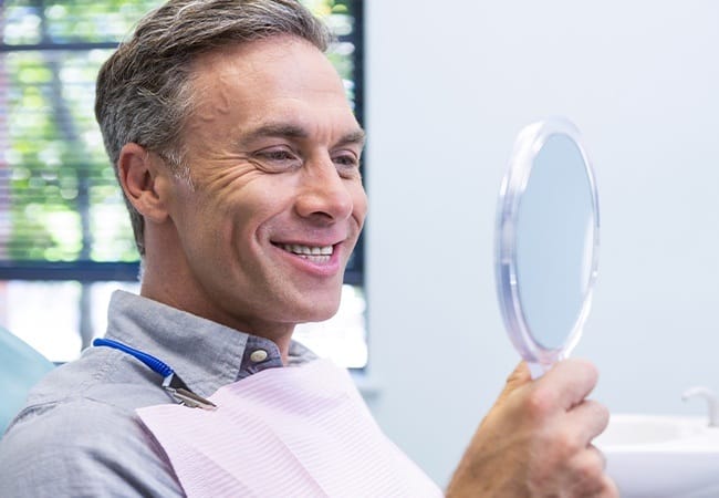 Man looking at smile after full mouth reconstruction