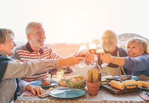 Group of older friends with dental implants in Pittsburgh enjoying a meal