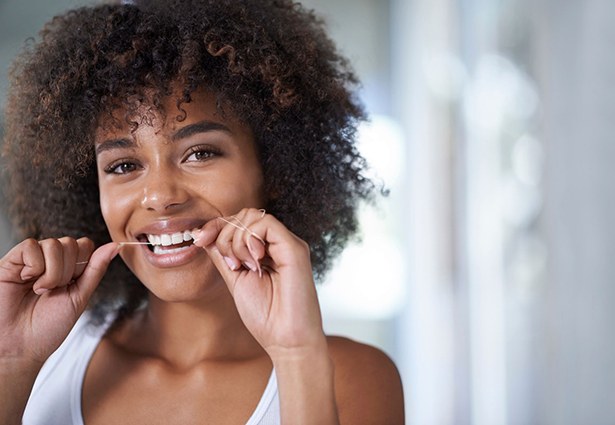 woman smiling while flossing her dental implants in Pittsburgh