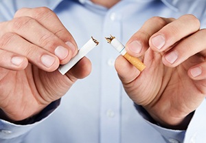 person breaking a cigarette in half
