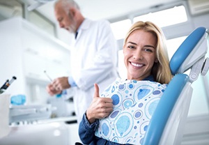 woman at a dental checkup giving a thumbs-up in the treatment chair