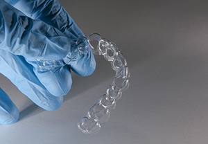 Gloved hand holding clear aligner