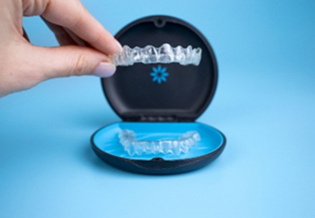 Patient placing Invisalign aligner in black and blue storage case