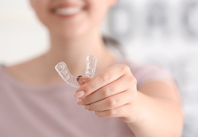 Patient holding their Invisalign aligner