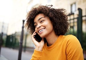Woman in orange shirt smiling while talking on phone