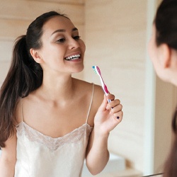 Woman brushing teeth to prevent dental emergency in Pittsburgh