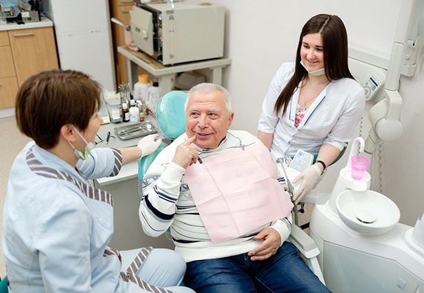 older man talking to dental team 