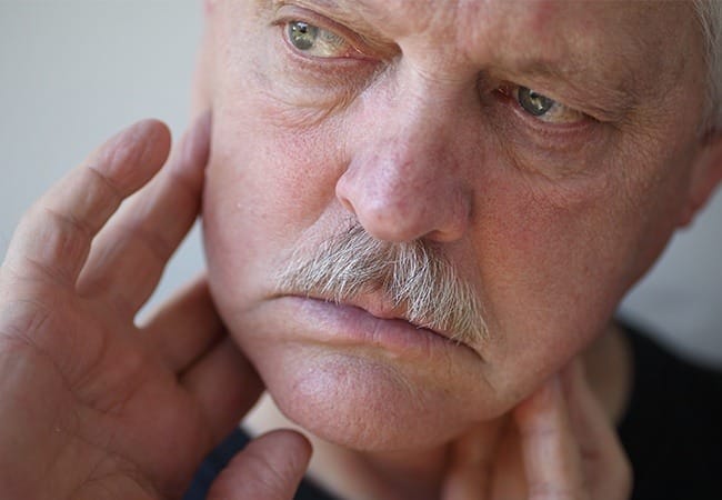Man in need of T M J therapy holding jaw
