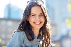 Woman with nice teeth smiling on summer city street