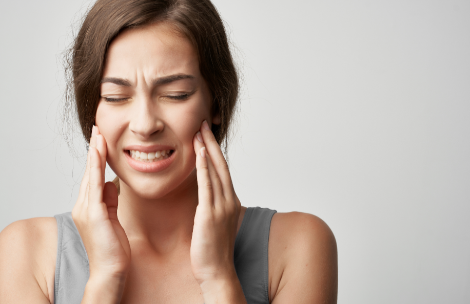 Woman holding jaw, wincing