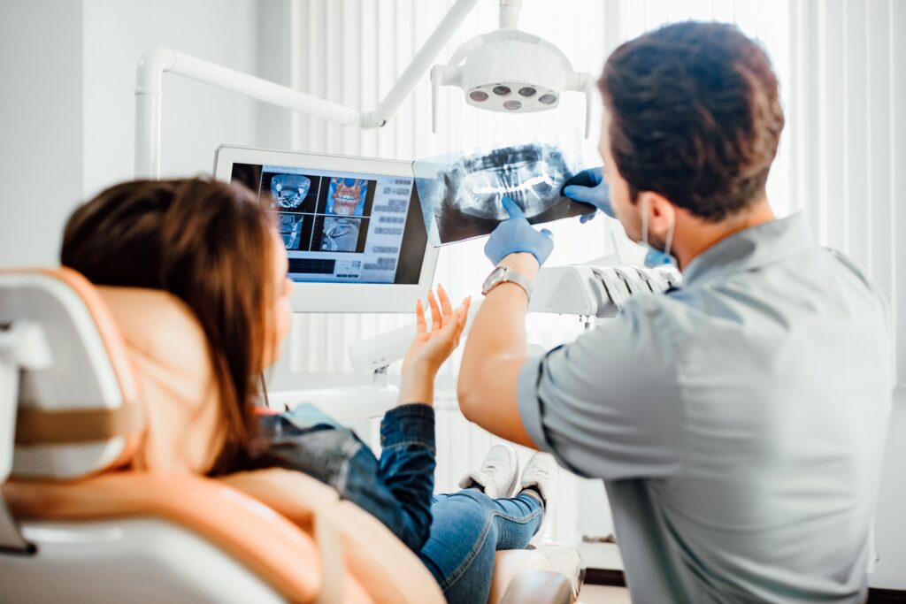 Dentist showing x-rays to patient in dental chair
