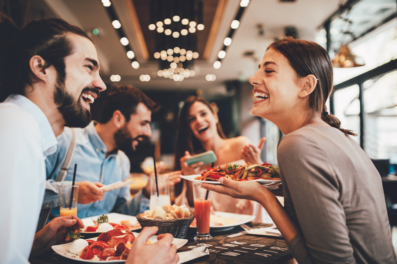 Patient with veneers smiling with friends at restaurant